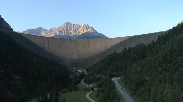 Massive incredible dam landscape of Schlegeis at Zillertal Alps Austria with a car cruising on the ghat section 
(wide shot)