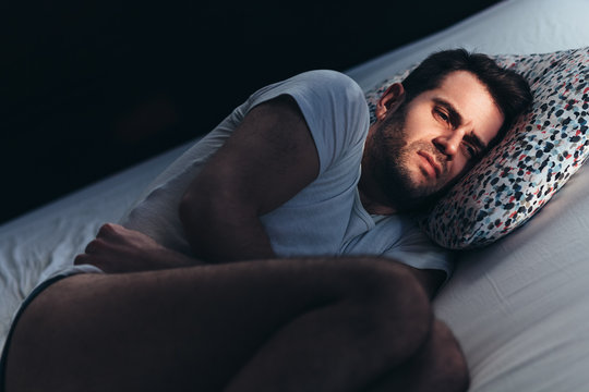 Young depressed man in pain on the bed
