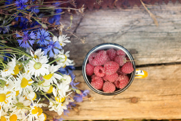 a bouquet of chamomiles and a cup full of raspberry