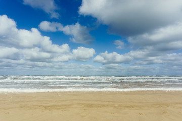 Beach with cloudy blue sky and waves at the sea background