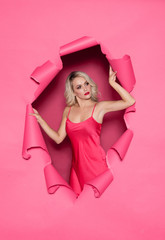 Young and beautiful woman in pink dress over torn paper background.