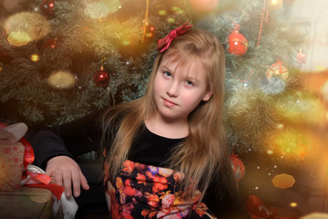 girl blonde child in black with red dress in christmas by the christmas tree