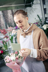 Attentive young florist working in boutique alone