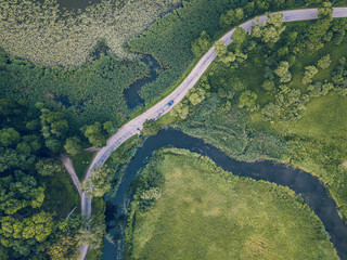 Drone Photo of Car Driving on the Road by the River under the Trees, Top Down View in Early Spring on Sunny Day - Concept of Peaceful Life in Countryside and Traveling, Freedom