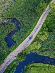 Aerial Photo of Car Driving on the Road going by the River under the Trees, Top Down View in Early Spring on Sunny Day