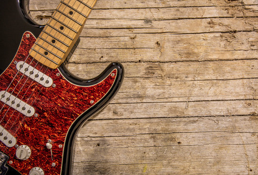 Close-up of electric guitar lying on vintage wood background, with copy space