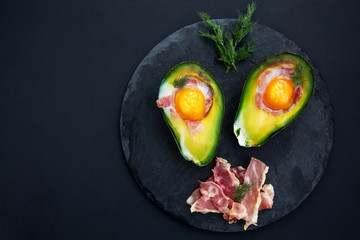 tasty baked avocado with an egg on a black background