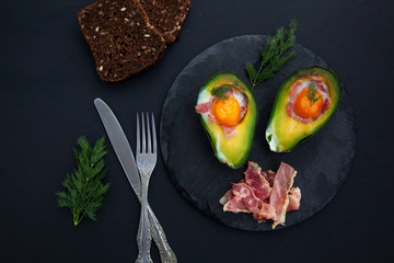 baked avocado with an egg on a black background