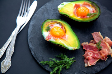tasty baked avocado with an egg on a black background