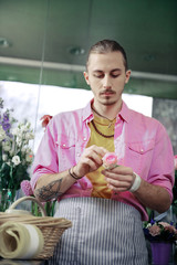 Concentrated bearded male person holding short flower