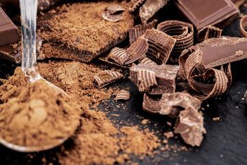Broken chocolate pieces and cocoa powder on a dark background