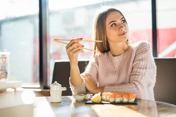 Young beautiful blond girl eating sushi of a Japanese restaurant