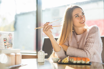 Young beautiful blond girl eating sushi of a Japanese restaurant