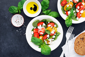 Healthy food. Salad of colored cherry tomatoes, cottage cheese, basil with olive oil, balsamic, sea salt, portioned black pepper. top view. On a gray dark background..