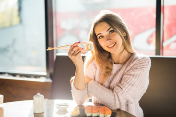 Young woman eats traditional sushi rolls at the restaurant