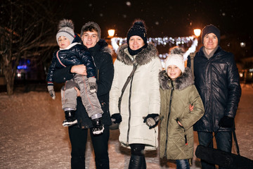 A good family of five people, two adults and three children have a rest, walk, have fun, spend family time in the winter night city