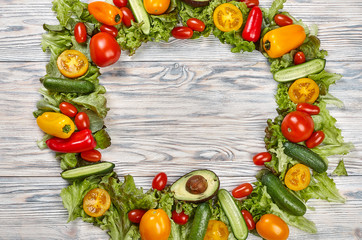 Tomatoes, cucumbers, green salad on a wooden background with space for the text.