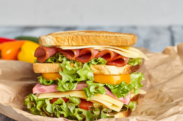 Big high sandwich on paper on wooden background