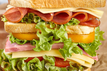 Big high sandwich on paper on wooden background