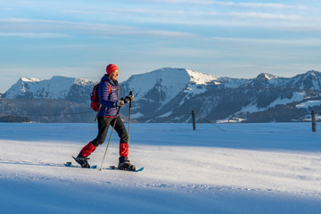 active senior woman snowshoeing in the Allgaeu Alps near Oberstaufen, Bavaria, Germany