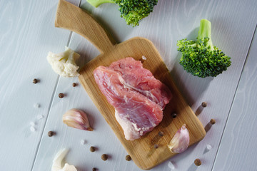 Pork for roasting on a cutting board, broccoli, garlic, salt, close-up