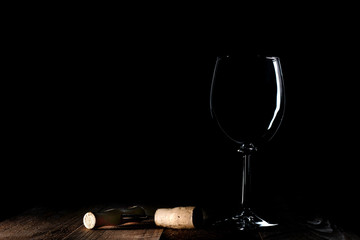 Empty wine glass and a corkscrew on a black background