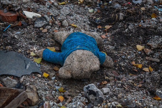 Toy dirty bear lies on the ground among the ruins