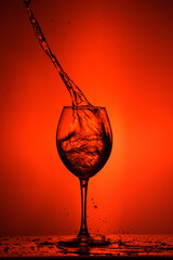 Naklejka na ściany i meble Wine glass. Splashes on a red background.