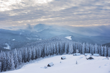 Fototapeta na wymiar Houses on the snowy mountain range with a view to the summit.