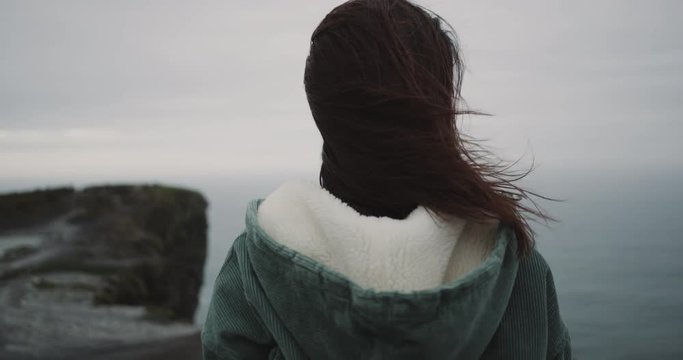 Amazing landscape young lady admire the Cliffs of Moher , closeup camera taking video from the back of the lady.