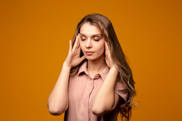 Fototapeta premium Young beautiful woman has headache, isolated on yellow background