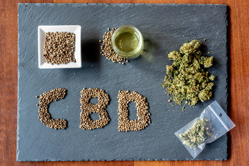 abbreviation of the active ingredient cbd on a slate with medical marijuana sprouts, hemp seeds,...