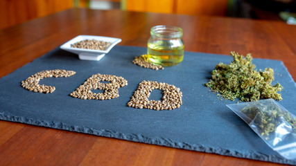 abbreviation of the active ingredient cbd on a slate with medical marijuana sprouts, hemp seeds,...