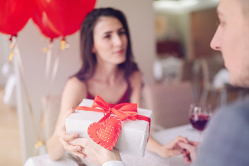 Valentine's Day concept. Happy couple in love with. A young loving couple celebrating Valentine's Day in the restaurant. Lovers give each other gifts. Romance restaurant for Valentine's Day- concept.