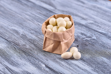 Colored candy in paper bags on wooden background