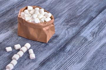 Colored candy in paper bags on wooden background