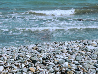 Beautiful seashore with small waves and colored stones
