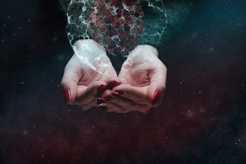 Woman hand holding cell dividing in plam. Nebula dust. Mixed media.