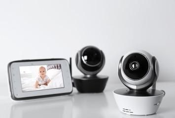 Modern security CCTV cameras and monitor with baby's image on table