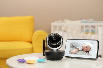 Modern security CCTV camera and monitor with baby's image on table. Space for text