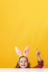 Cute little child girl with bunny ears at home is hunting for Easter eggs.
