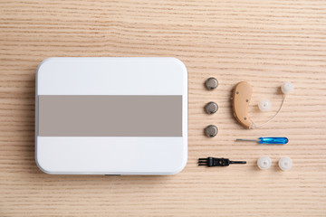 Flat lay composition with hearing aid and accessories on wooden background