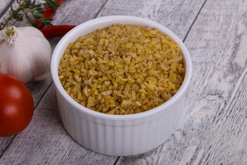 Raw bulgur in the bowl with tomatoes and garlic