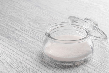 Glass transparent container with sugar on a white old wooden table