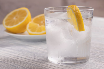 Refreshing cold water with lemon. With ice. Ready to eat. Next is a knife after cutting fruit. Misted glass.