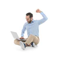 Emotional young man with laptop celebrating victory on white background