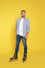 Full length portrait of young man with inline roller skates on color background