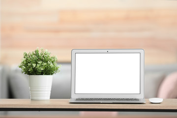 Laptop with blank screen on table indoors. Space for text