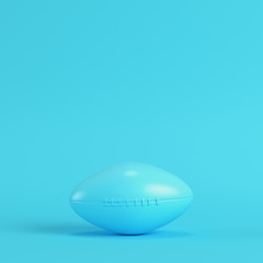 American football ball on bright blue background in pastel colors