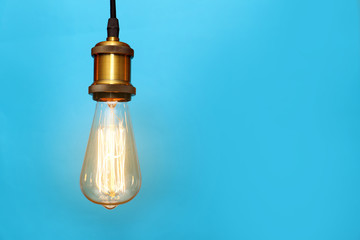 Pendant lamp with light bulb on color background, space for text